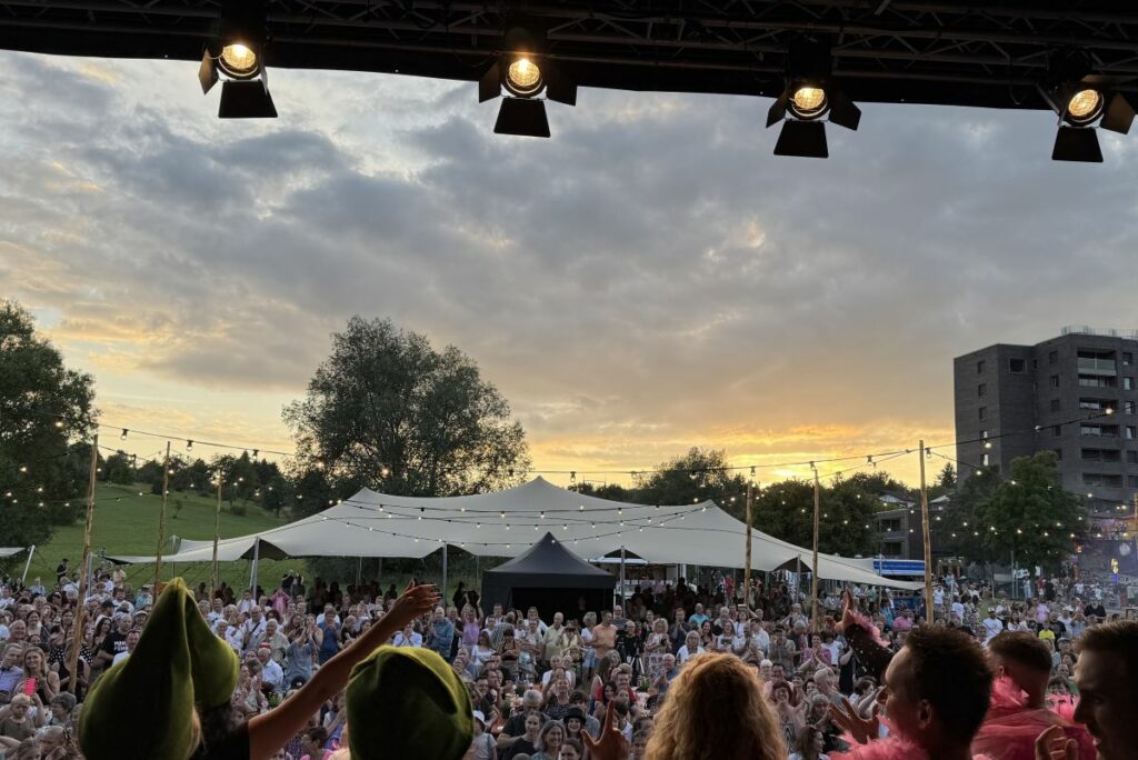 Publikum bei einem Gartenfest vor Bühne und Stretchzelten in stimmungsvoller Abendatmosphäre