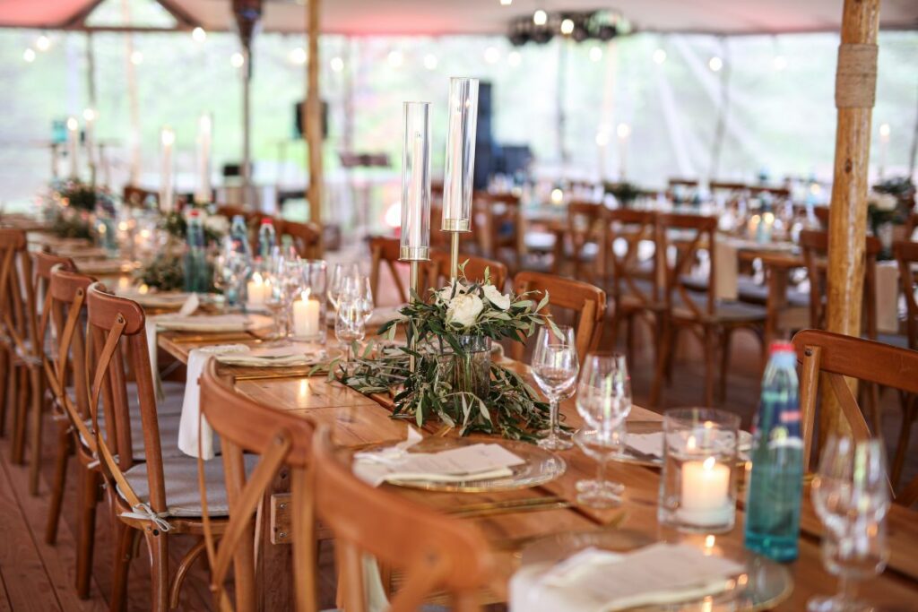 Festlich gedeckte Hochzeitstafel unter einem Stretchzelt im Schwarzwald mit Kerzen und Holzmöbeln