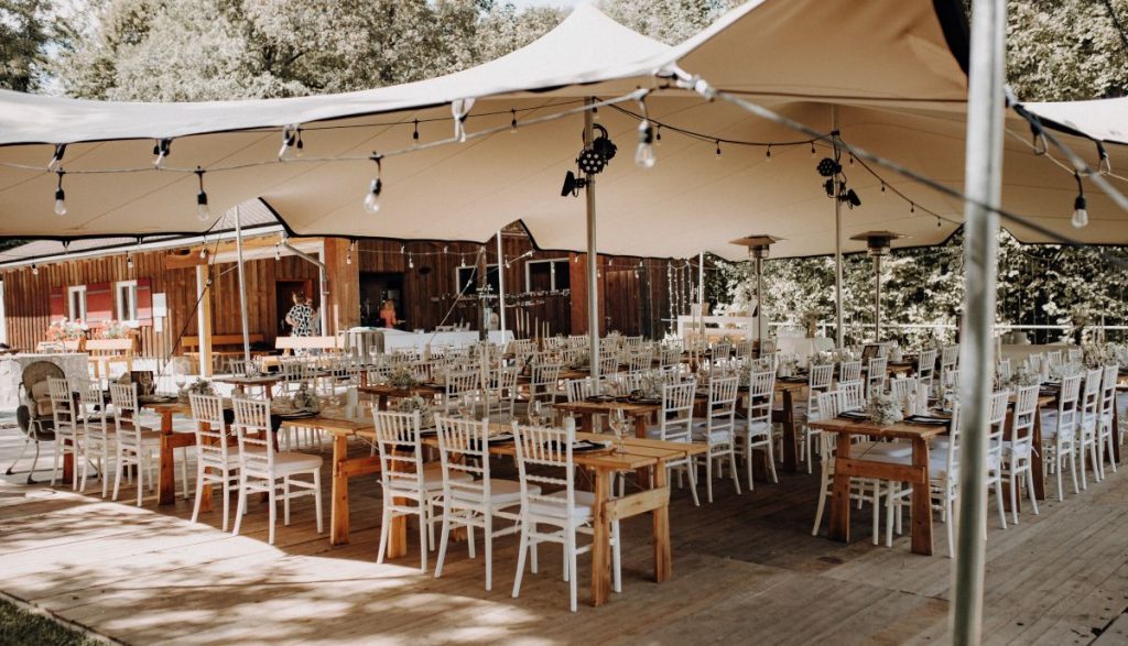 Stretchzelt bei Outdoor-Hochzeit mit gedeckten Tischen auf Holzterrasse