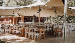 Stretchzelt bei Outdoor-Hochzeit mit gedeckten Tischen auf Holzterrasse